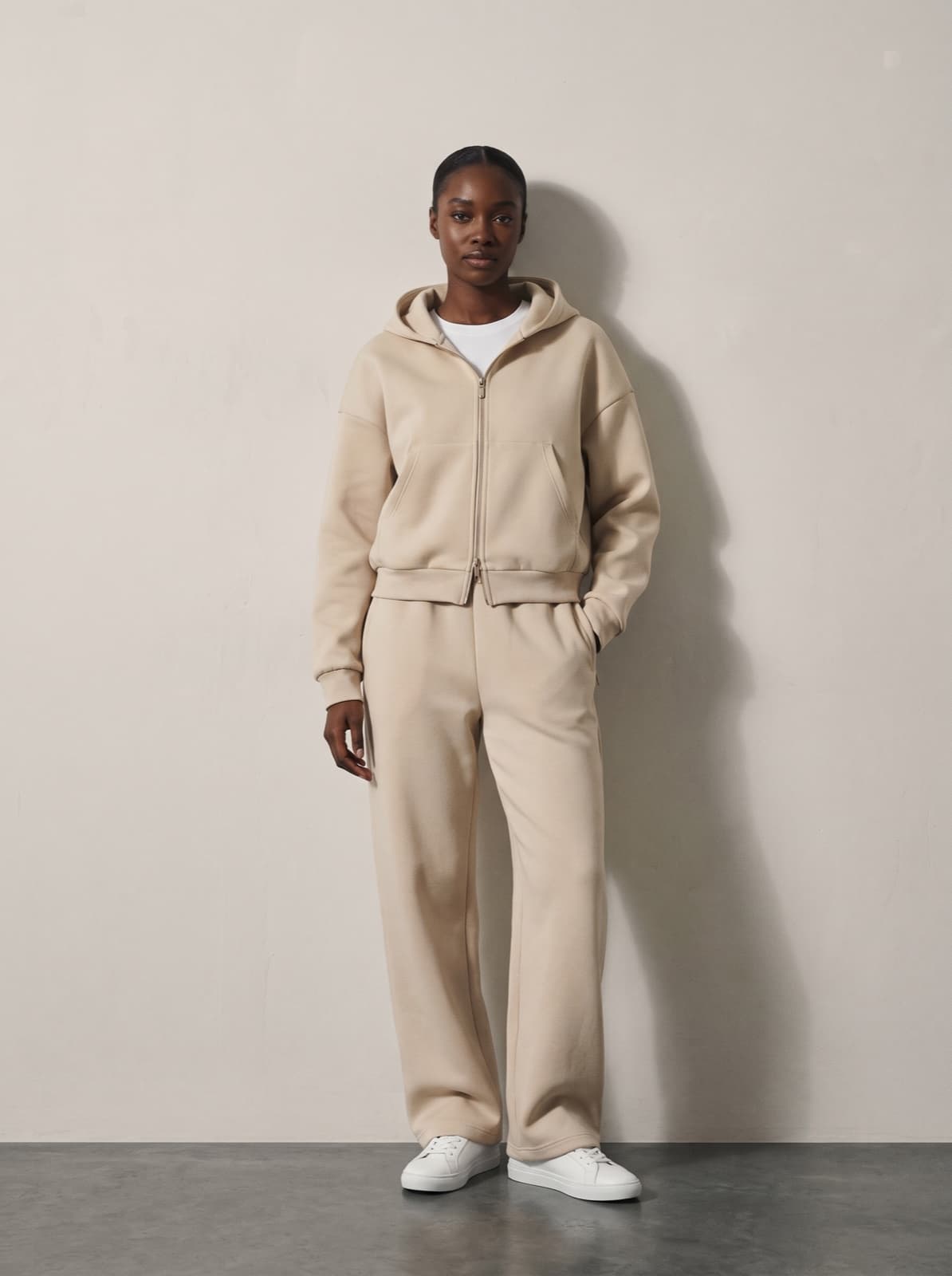 A model wearing the matched Chelsea Zip Hoodie and trousers in beige